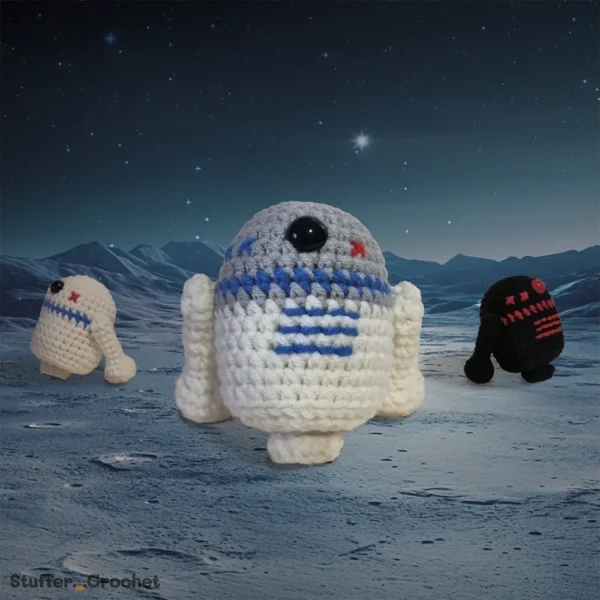 Three crocheted space robot plush toys in white, gray, and black.